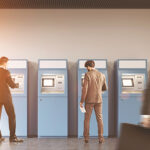 Customers using a bank of ATMs serviced by a top NCR service company that keeps these machines running